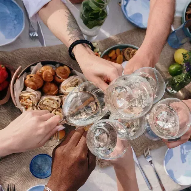 Overhead shot of a group of people clinking glasses at a brunch table.